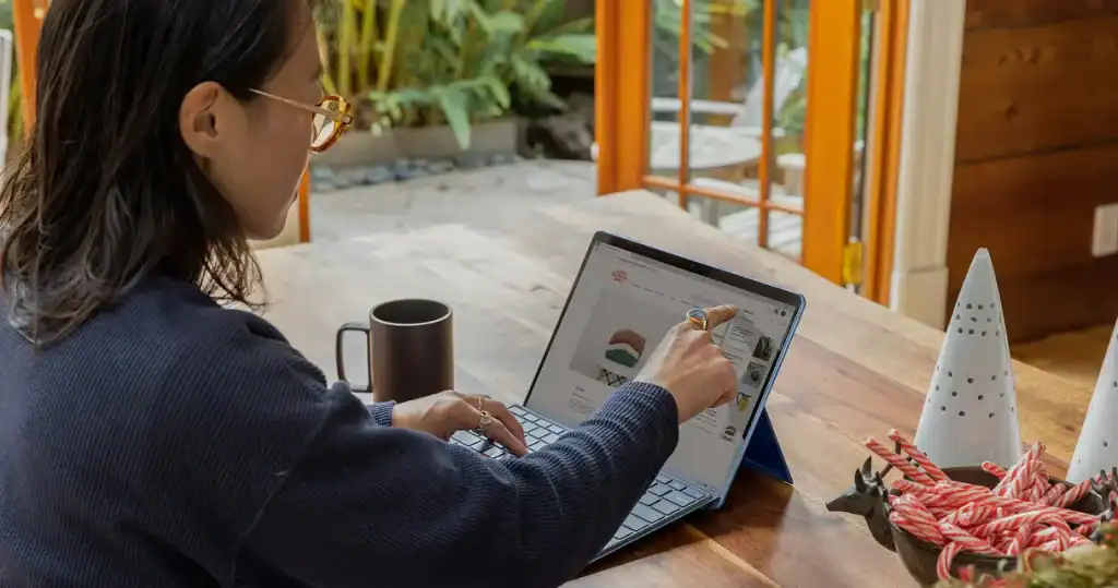 Woman working on a tablet at a cozy cafe with DMLY branding visible.